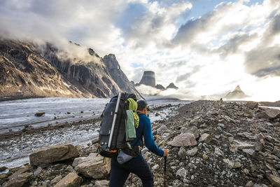 Man standing on rock against sky