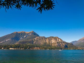 Scenic view of sea and mountains against clear blue sky