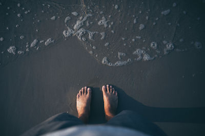 Low section of man standing at beach