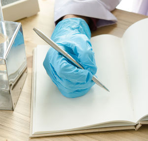 Cropped hand of scientist writing in book at laboratory