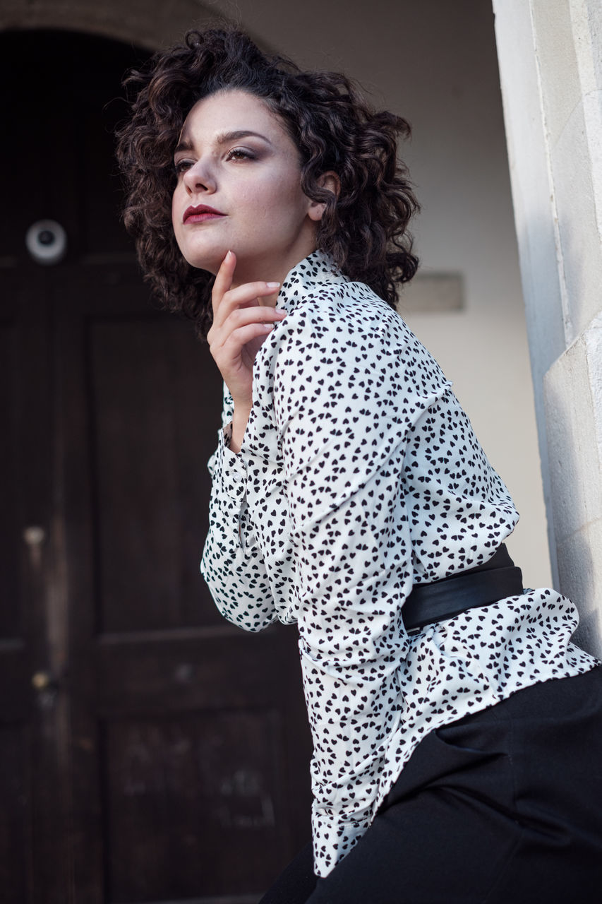 one person, adult, curly hair, fashion, women, photo shoot, young adult, hairstyle, portrait, indoors, polka dot, clothing, brown hair, black, female, looking, standing, lifestyles, architecture, person, spotted, pattern, waist up, contemplation