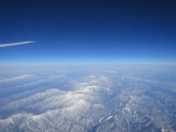 Aerial view of snowcapped mountains against clear blue sky