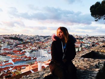 Woman looking at city buildings against sky