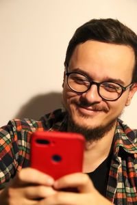 Portrait of young man holding gift against pink background
