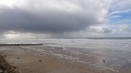 Scenic view of beach against cloudy sky