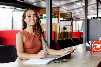 Portrait of a charming girl working or studying in a cafe., making notes in a notebook