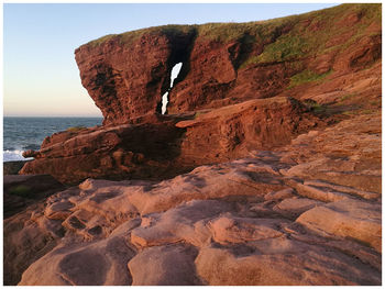 Rock formation by sea against clear sky