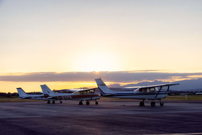 Airplane on airport runway against sky during sunset