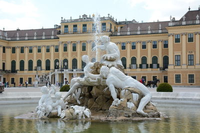 Statues by fountain against buildings in city