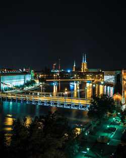 High angle view of illuminated bridge over river by buildings in city at night