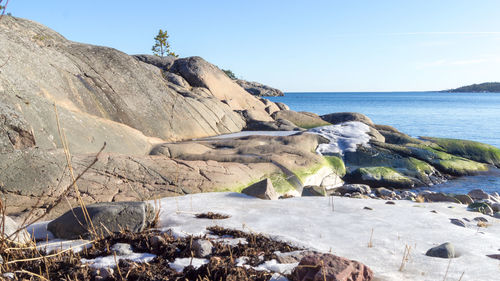 Rocks on beach against clear sky