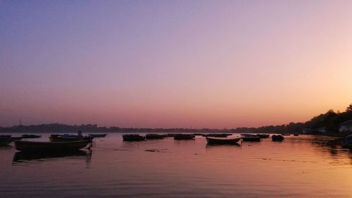 Boats moored in sea against sky during sunset