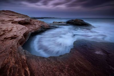 Rock formations on shore against sky