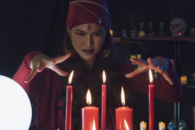 Female fortune teller with burning candles at home