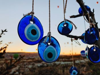 Close-up of blue evil eyes hanging against sky during sunset