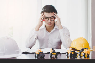 Tensed male architect working at desk in office