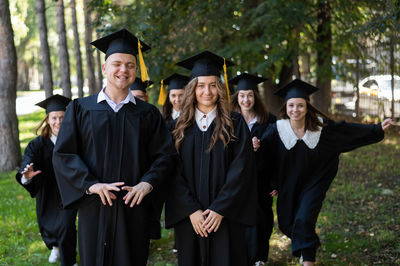 Portrait of woman wearing graduation gown standing in forest