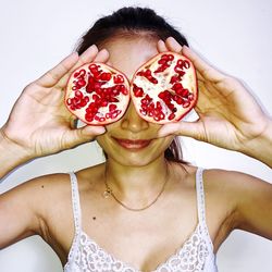 Smiling woman holding halved pomegranate against white background