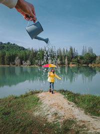 Rear view of woman with arms outstretched standing in lake