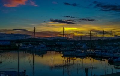 Sailboats moored at harbor against sky during sunset