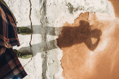 Close-up of man holding umbrella standing against wall