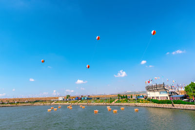 Hot air balloons flying over river against blue sky