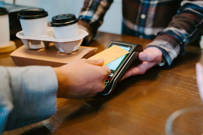 Midsection of man holding coffee cup on table