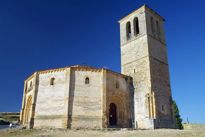 Low angle view of old building against clear blue sky