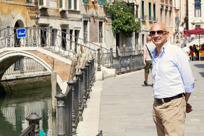 Senior man standing by footbridge in city