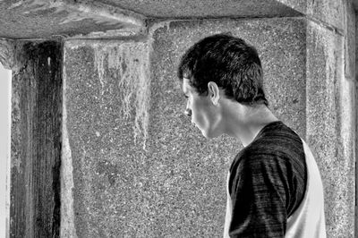 Side view of man standing by concrete wall