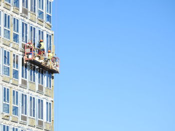 Low angle view of construction site against clear blue sky