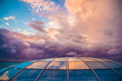 Low angle view of glass building against sky during sunset