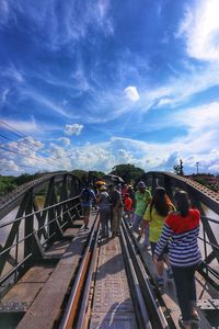 People on railway bridge against sky