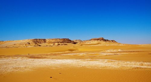 Scenic view of desert against clear blue sky