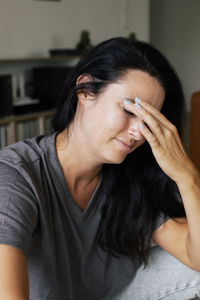 Stressed woman touching forehead while sitting at home