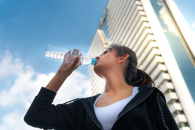 Low angle view of man drinking glass against sky