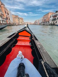 Low section of person on boat in canal against buildings