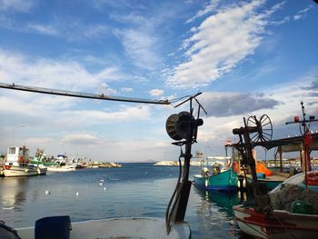 Fishing boats moored at harbor against sky