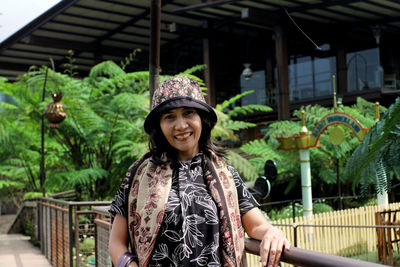 Portrait of smiling young woman standing against built structure