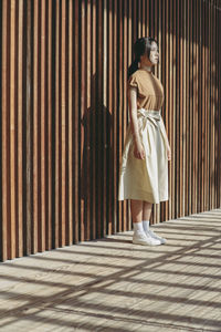 Young woman standing against wall