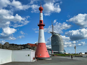 Lighthouse amidst buildings against sky