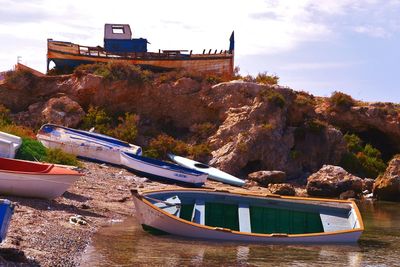 Boats moored at sea by rock formation against sky