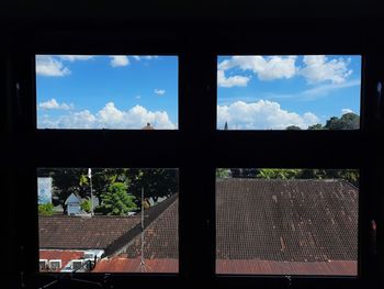 Silhouette trees and buildings against sky seen through window