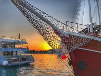 Sailboats moored in sea against sky during sunset