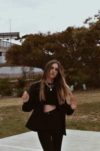 Beautiful young woman standing against trees and plants