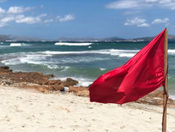 Red flag on beach against sky