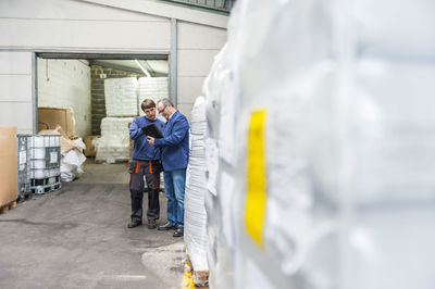 Manager and worker in storage of plastics factory checking products