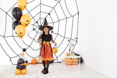 Rear view of girl with umbrella standing against wall during halloween