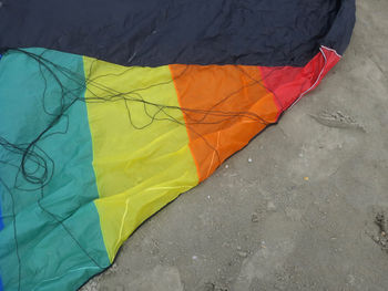 A part of a kite in rainbowcolors with black threads laying on the beach of velsen netherlands