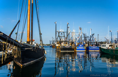 Boats moored in sea against blue sky